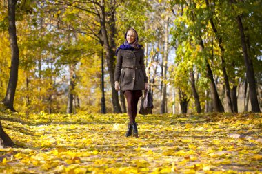 Genç kadın sonbahar parkında yürüyor.