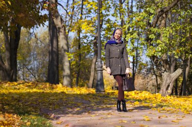 Genç kadın sonbahar parkında yürüyor.