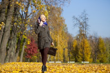 Genç kadın sonbahar parkında yürüyor.
