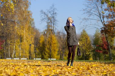 Genç kadın sonbahar parkında yürüyor.