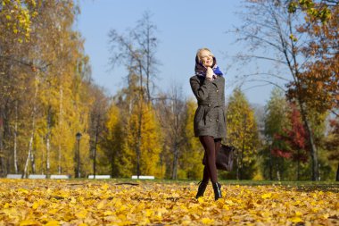 Genç kadın sonbahar parkında yürüyor.