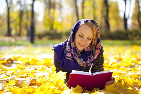 Krásná mladá dívka leží na podzim listy s Červená kniha — Stock fotografie