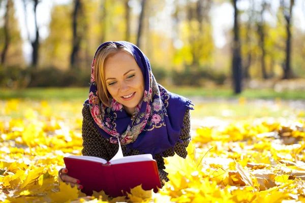 Krásná mladá dívka leží na podzim listy s Červená kniha — Stock fotografie