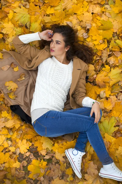 Genç güzel kız mavi Jeans sarı yapraklarda yalan — Stok fotoğraf