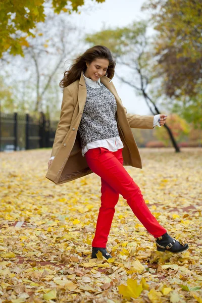 Young woman in fashion coat walking in autumn park — Stock Photo, Image