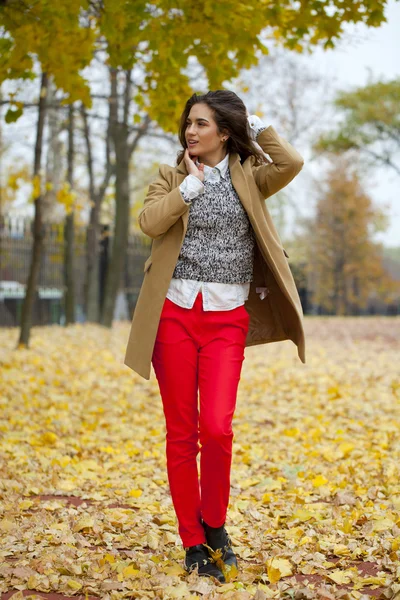 Junge Frau in Modemantel spaziert durch Herbstpark — Stockfoto