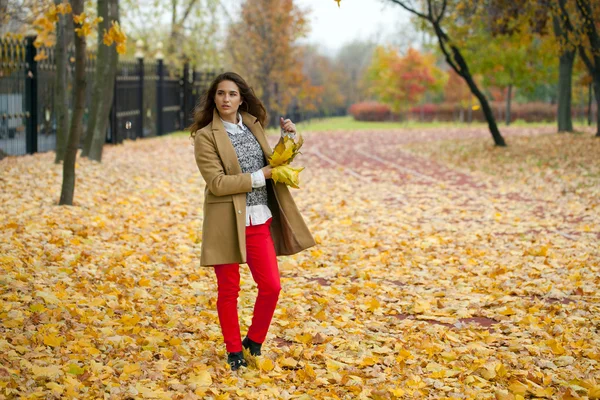 Young woman in fashion coat walking in autumn park — Stock Photo, Image