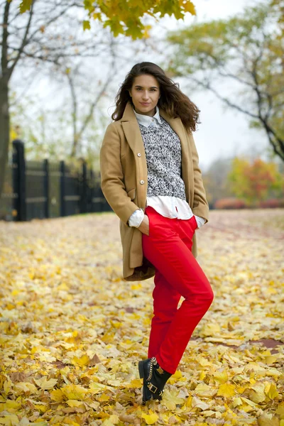 Young woman in fashion coat walking in autumn park — Stock Photo, Image