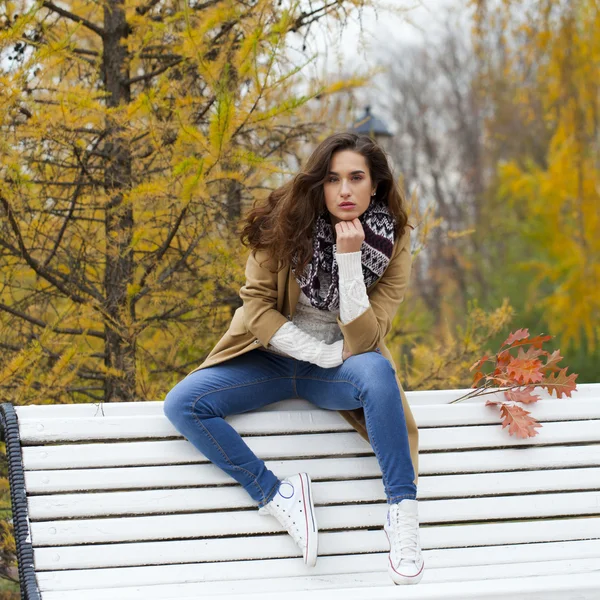 Mulher bonita sentada em um banco no parque de outono — Fotografia de Stock