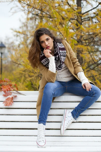 Sonbahar parkta bir bankta oturan güzel kadın — Stok fotoğraf