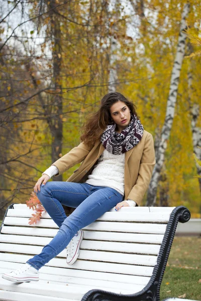 Mulher bonita sentada em um banco no parque de outono — Fotografia de Stock