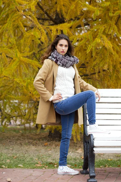 Young woman in fashion coat walking in autumn park — Stock Photo, Image