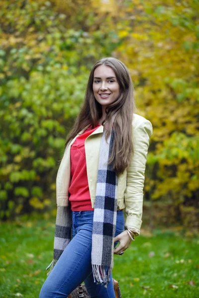 Jeune femme en manteau de mode marche dans le parc d'automne — Photo