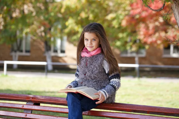 Beautiful little girl sitting on a bench — Stock Photo, Image