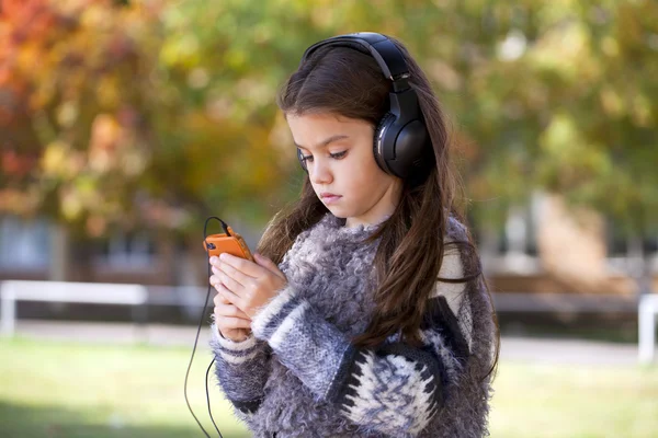 Belle petite fille écoutant de la musique sur écouteurs — Photo