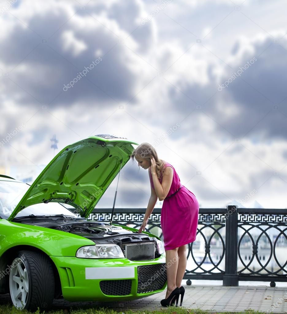 Young woman looks into the open hood 