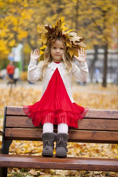 Güzel küçük bir kız bir bankta oturan — Stok fotoğraf