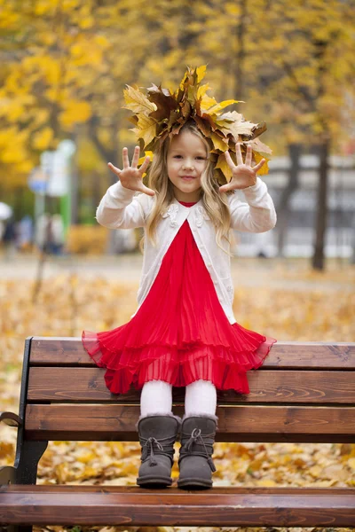 Beautiful little girl sitting on a bench — Stock Photo, Image