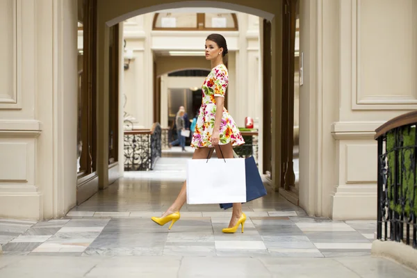 Hermosa mujer en vestido de flores rojas en la tienda — Foto de Stock