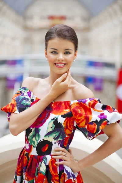 Mooie vrouw in rode bloemen jurk in de winkel — Stockfoto