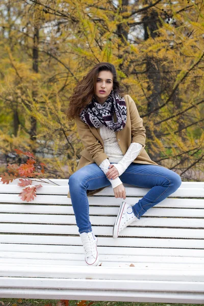 Hermosa mujer sentada en un banco en el parque de otoño — Foto de Stock