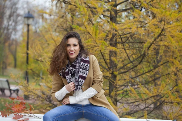 Mulher bonita sentada em um banco no parque de outono — Fotografia de Stock