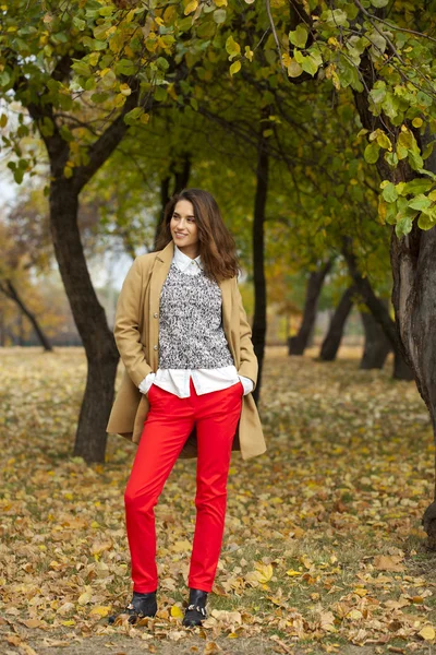 Jonge vrouw met mode vacht wandelen in herfst park — Stockfoto