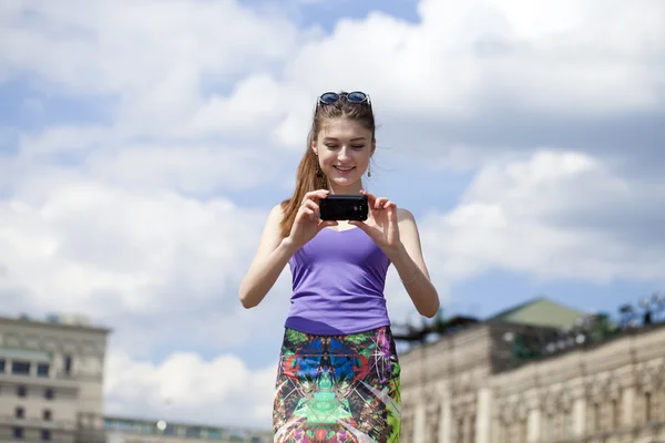 Gelukkig mooi meisje gefotografeerd op een mobiele telefoon — Stockfoto