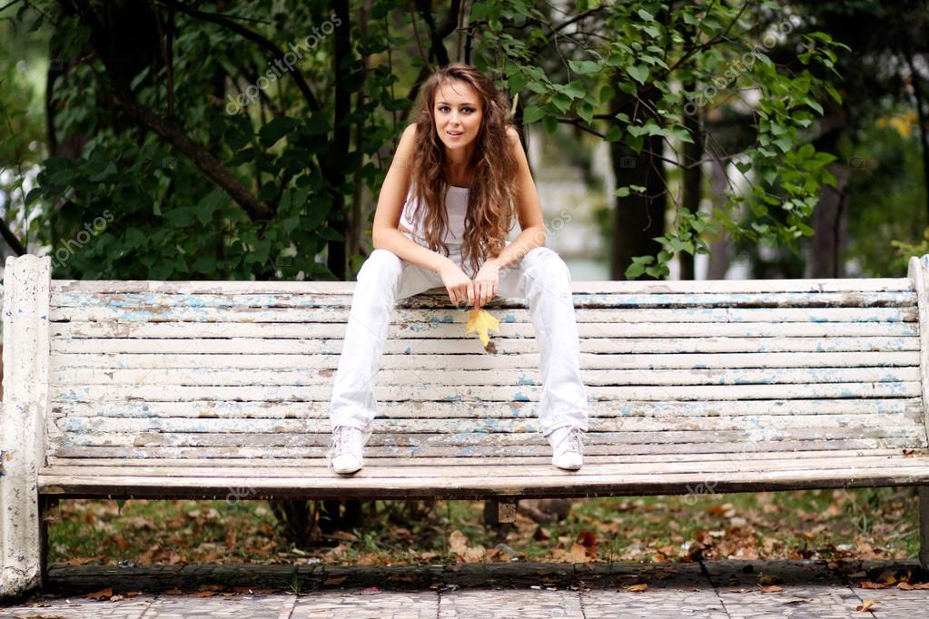 Beautiful woman sitting on a bench in autumn park