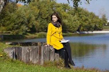 Sonbahar parkta bir bankta oturan güzel kadın