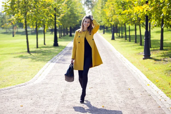 Mulher feliz no casaco amarelo andando rua outono — Fotografia de Stock