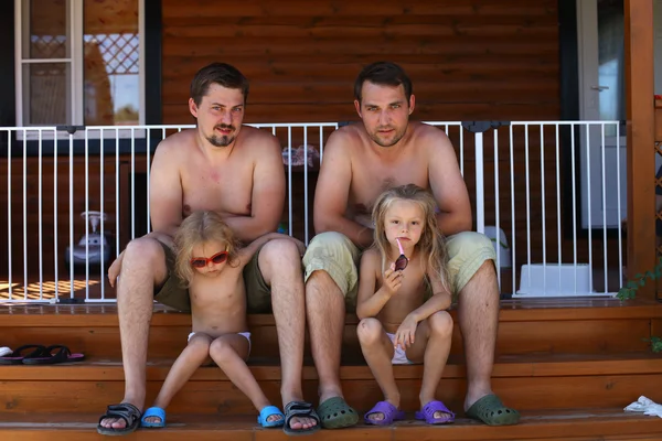 Two father sitting on the steps with their young daughters — Stock Photo, Image