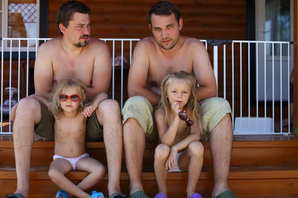Два отца сидят на ступеньках со своими маленькими дочерьми — стоковое фото