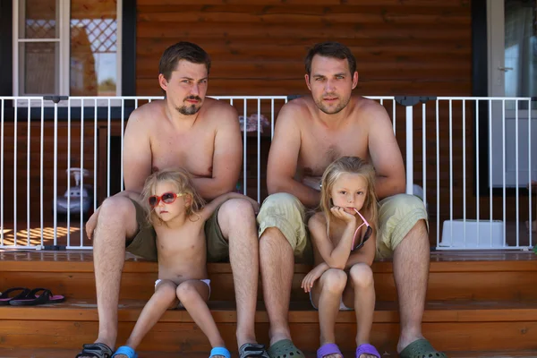 Two father sitting on the steps with their young daughters — Stock Photo, Image