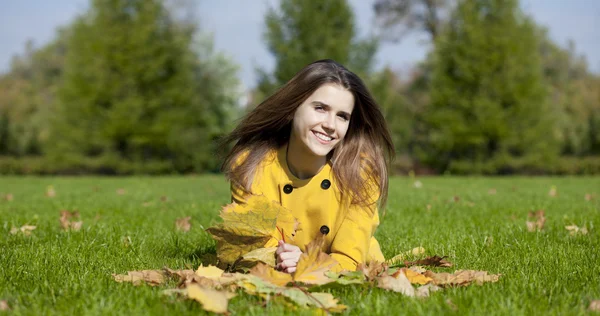 Mujer joven feliz en abrigo amarillo en el parque de otoño — Foto de Stock