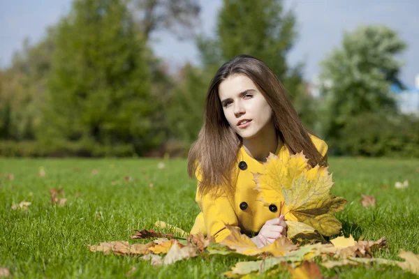 Happy young woman in yellow coat in autumn park — Stock Photo, Image