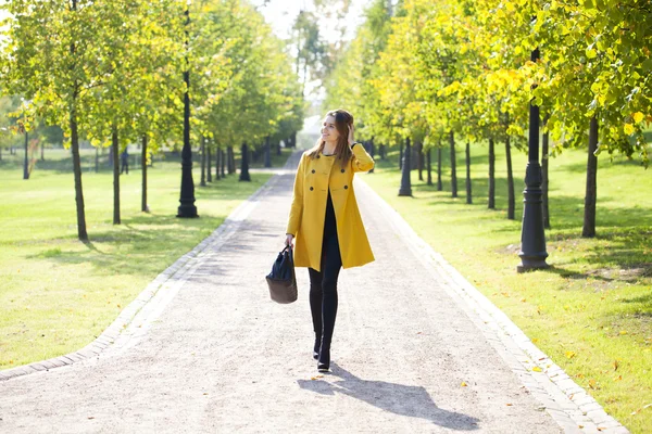 Hermosa mujer sentada en un banco en el parque de otoño — Foto de Stock