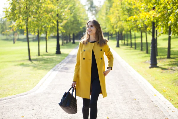 Giovane donna felice in cappotto giallo in strada autunno — Foto Stock