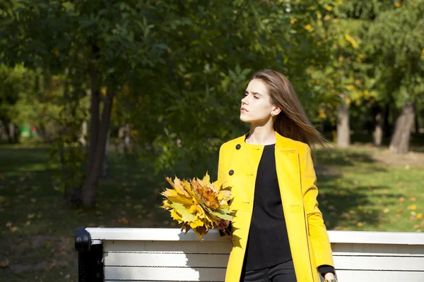 Mujer joven feliz en abrigo amarillo en la calle de otoño —  Fotos de Stock