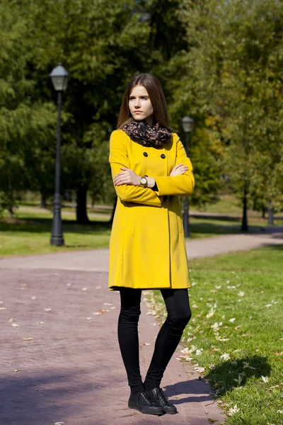 노란색 코트가 거리를 걷고 있는 행복 한 여자 — 스톡 사진