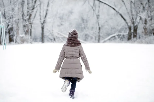 Niña feliz corriendo sobre el fondo del invierno cubierto de nieve — Foto de Stock