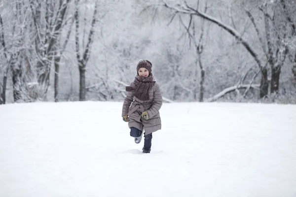 Ευτυχισμένη κοριτσάκι τρέχει στο παρασκήνιο των χιόνι κάλυψε π — Φωτογραφία Αρχείου