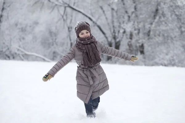 Щаслива маленька дівчинка біжить на тлі снігового покритого батога — стокове фото
