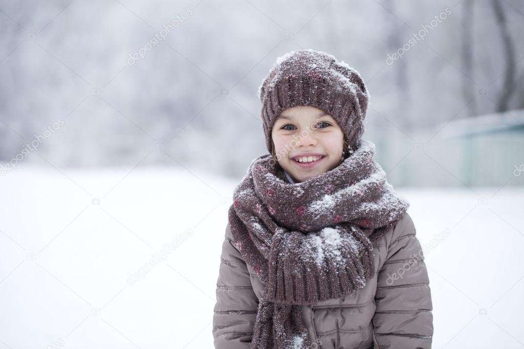 Happy little girl on the background of a winter park