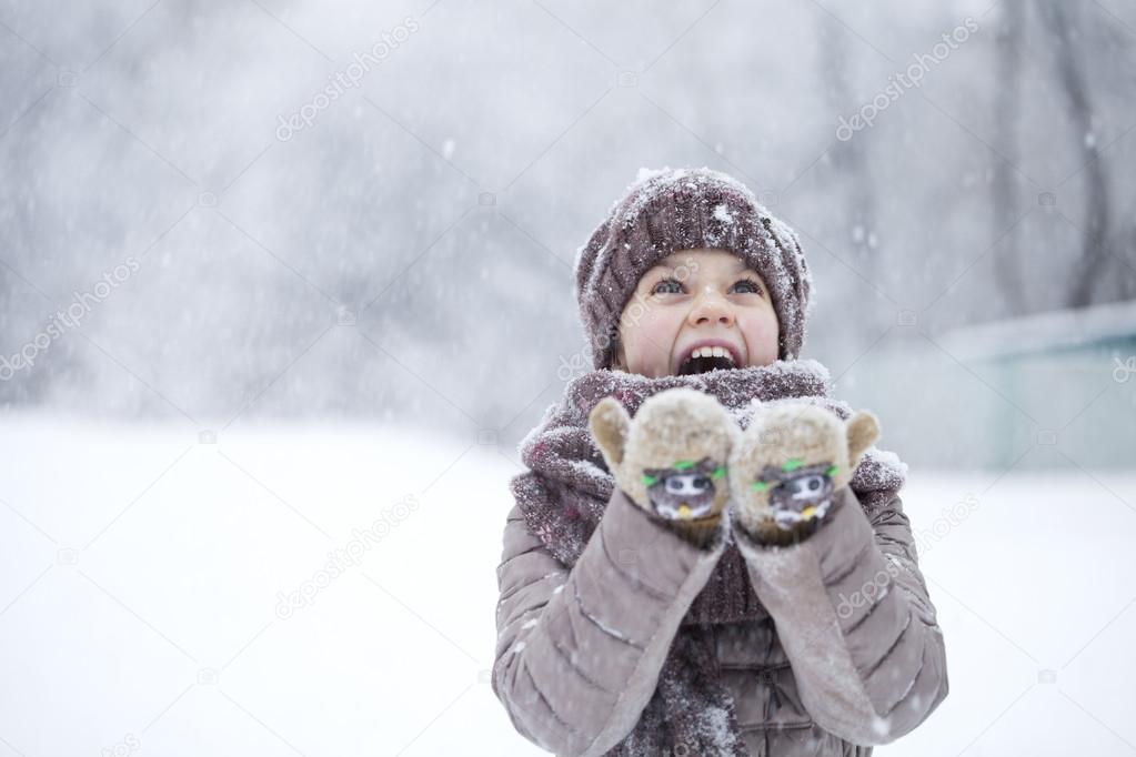 Portrait of a happy little girl on the background of a winter pa