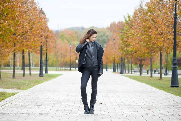 Femme heureuse en manteau noir marchant rue automne — Photo