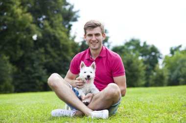 Genç adam parkta köpeğiyle oynuyor.