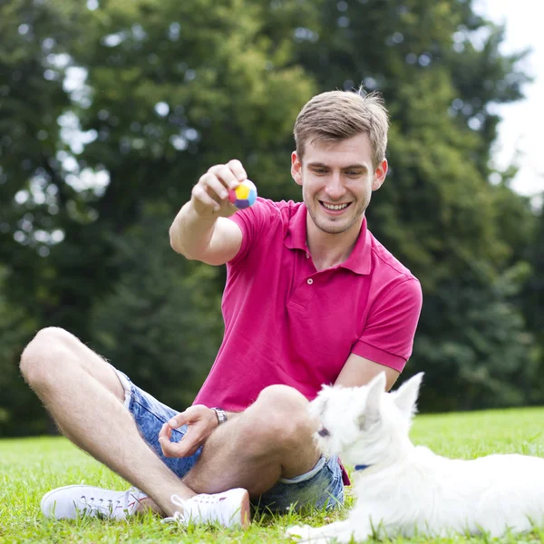 Jovem brincando com seu cão no parque — Fotografia de Stock