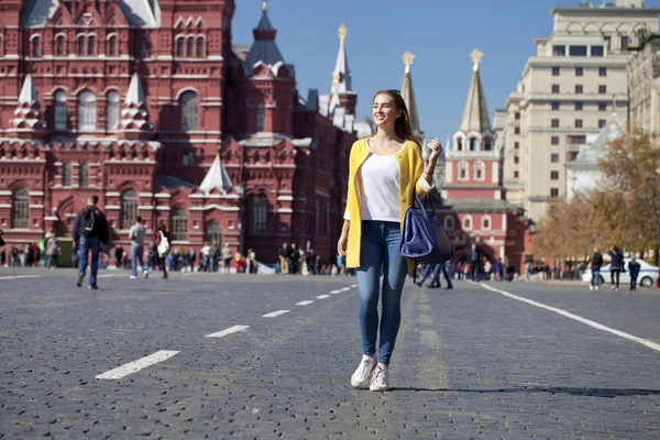Young woman in yellow coat walks on the Red Square in Moscow — Stock Photo, Image