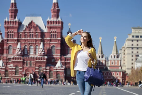 Happy young woman in yellow coat in autumn street — Stock Photo, Image